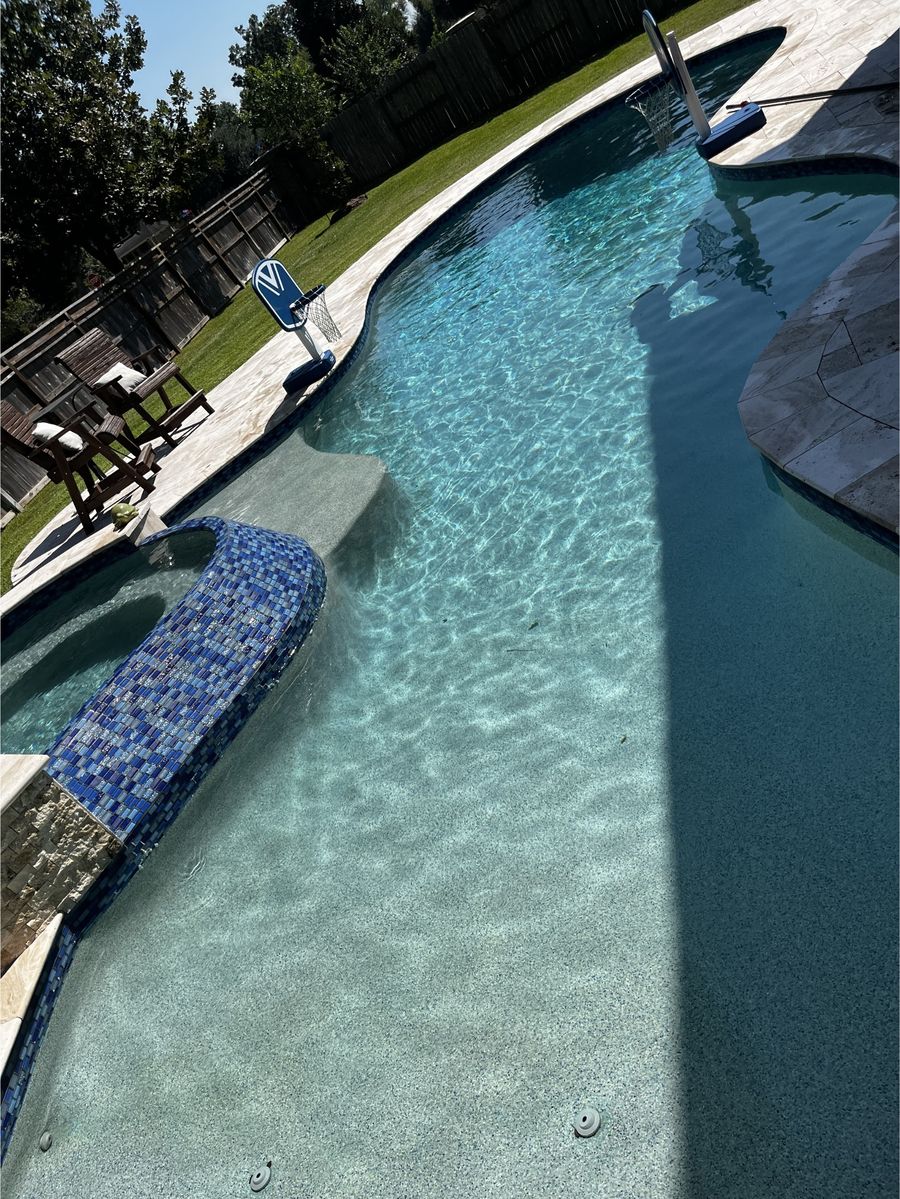 Long backyard pool with clear blue water after professional cleaning in the Austin area