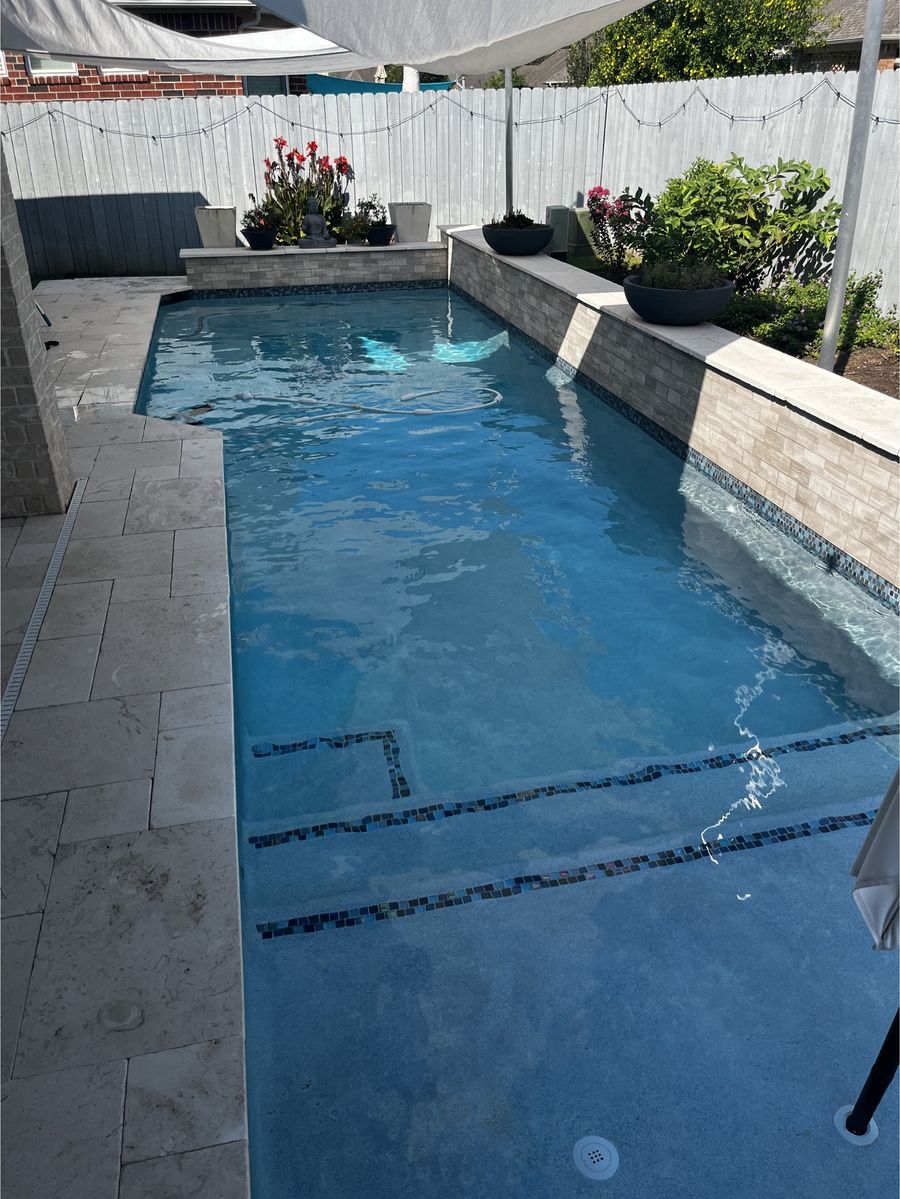 Backyard pool with stone features and clean water beside a green lawn