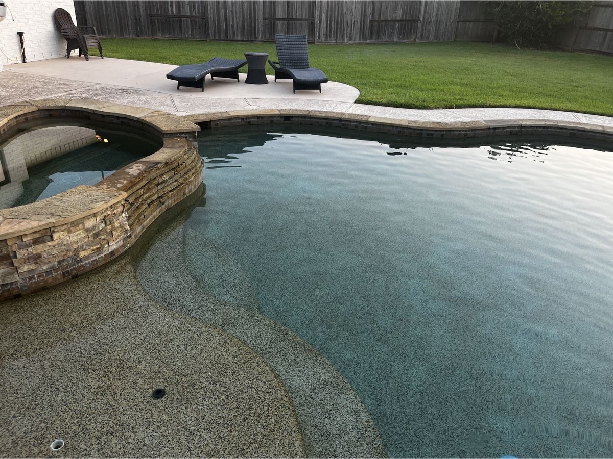 Freeform pool with tanning ledge and stacked-stone spa after cleaning near Austin, TX